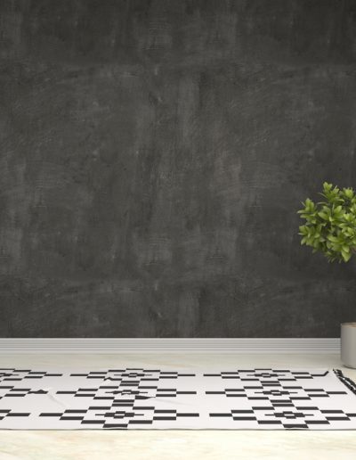 Minimalist living room with large window, grey textured wall, geometric rug, and green potted plant.