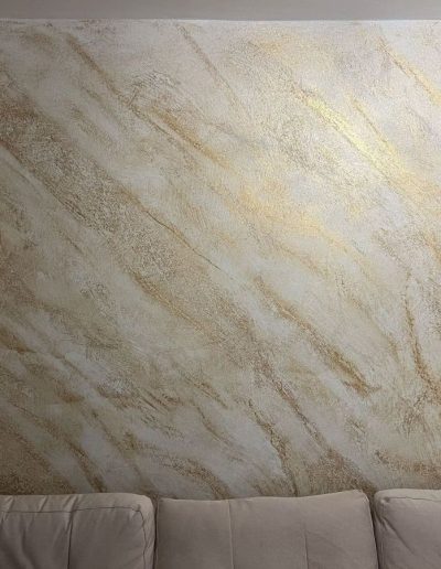 Elegant cream marbled wall with gold accents, beige tiles, and plush sofa in modern luxury interior.