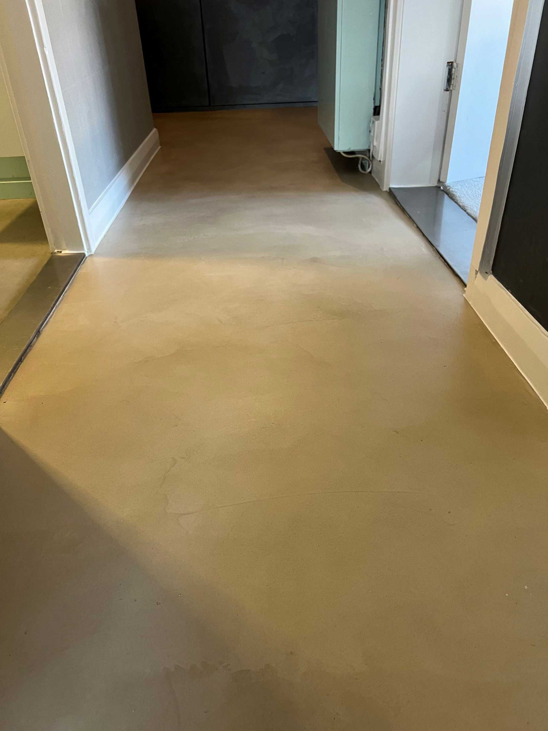 Smooth beige microcement flooring in a residential hallway